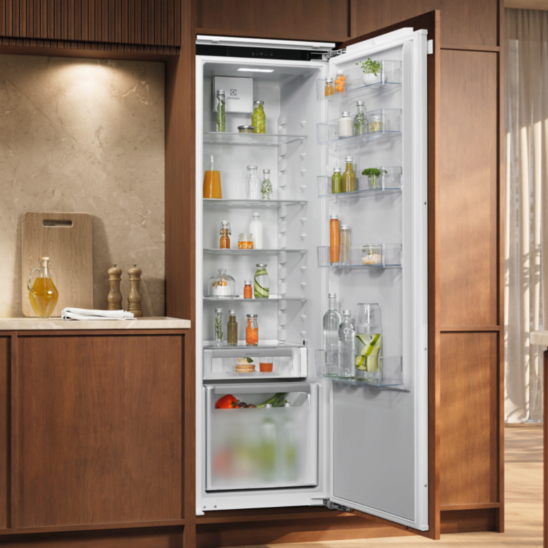 Open Electrolux refrigerator in a kitchen with wooden cabinets and a cutting board.