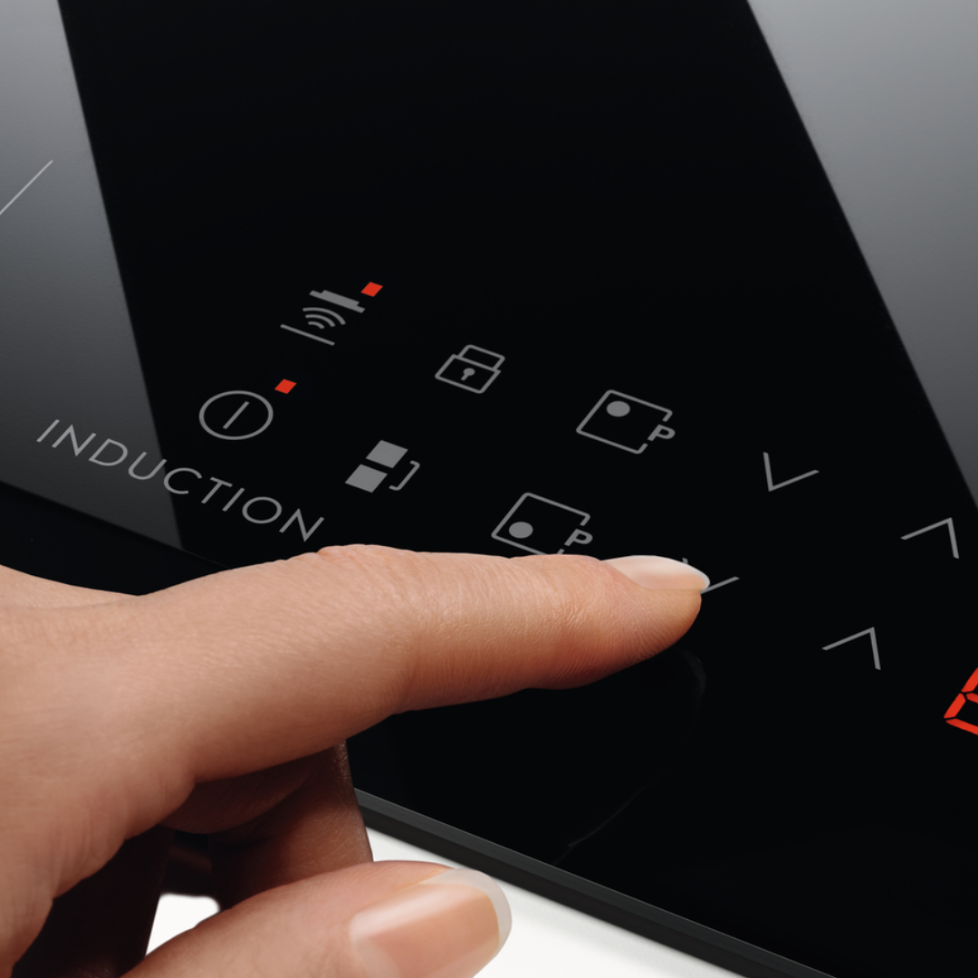 Hand pressing a button on an Black Electrolux Induction Hob device with various icons displayed.