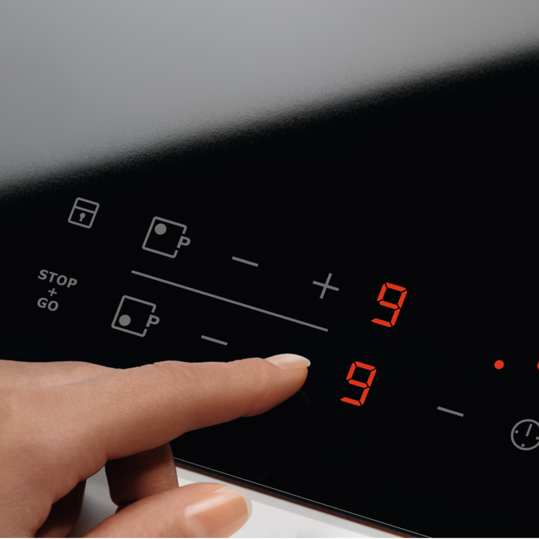 Hand pressing a button on an Electrolux Ceramic Hob with digital display