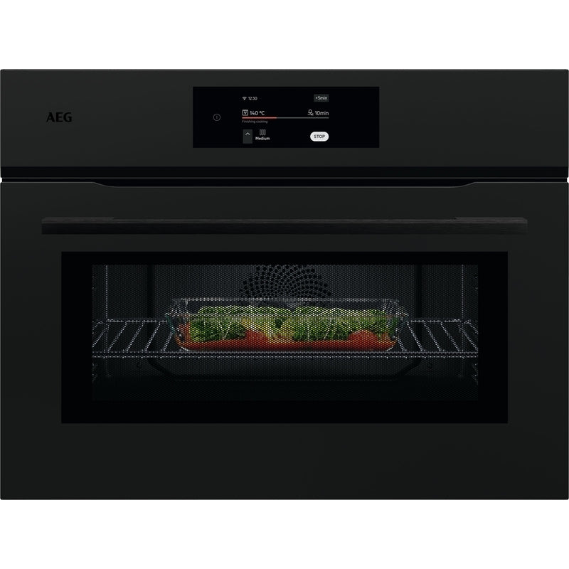 Black AEG combi oven with a dish of vegetables inside on a white background