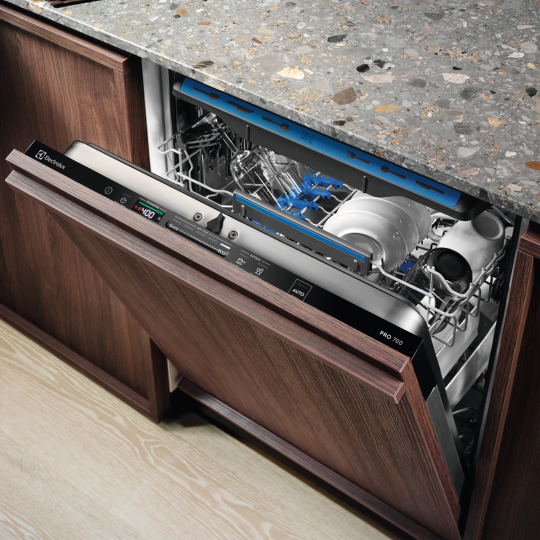 Open Electrolux Integrated dishwasher with clean dishes inside, placed under a kitchen counter.