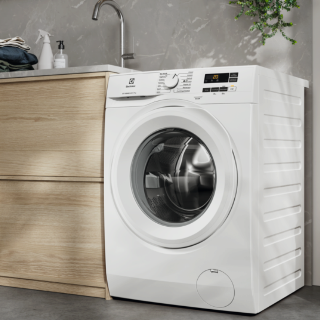 White Electrolux washing machine in a modern laundry room with wooden cabinets and a gray countertop.