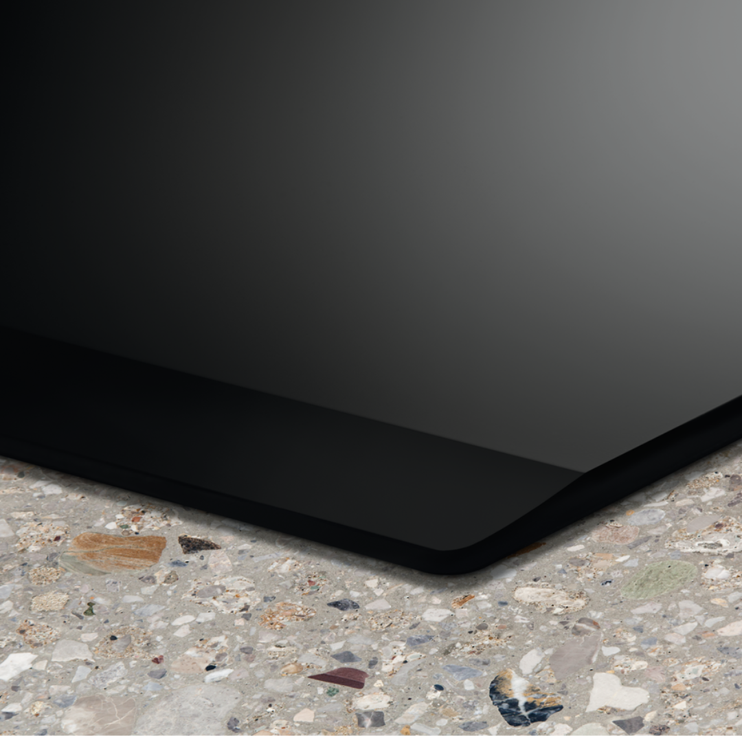 Black Electrolux induction hob on a textured concrete surface with a dark background