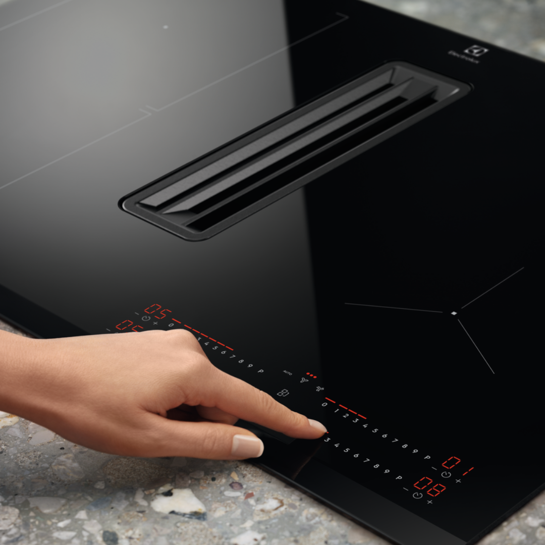Person adjusting settings on a modern Electrolux Black Extraction induction Hob