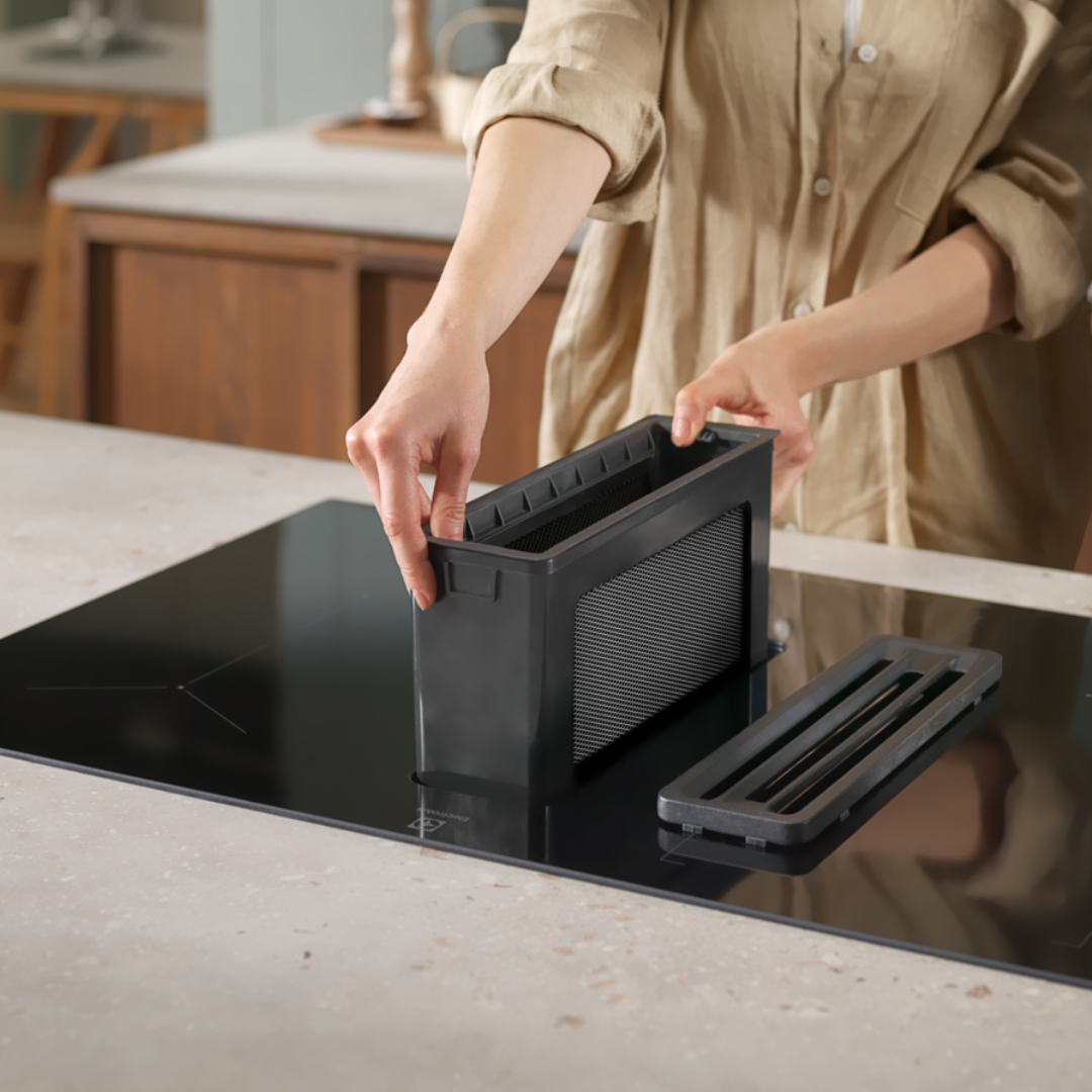 Person taking filter out of Electrolux Black Extraction induction Hob