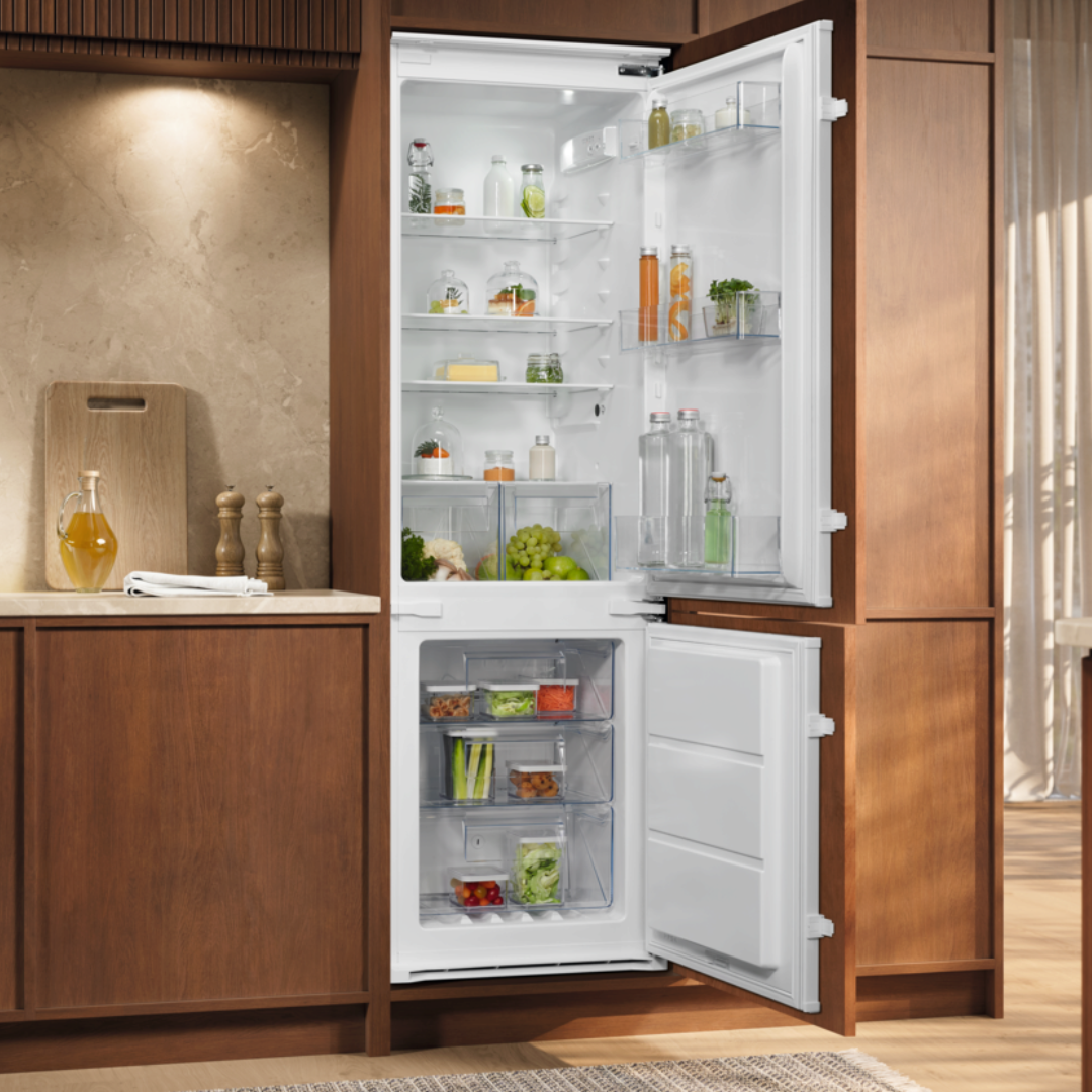 Open Electrolux refrigerator in a kitchen with wooden cabinets and a neutral color scheme.