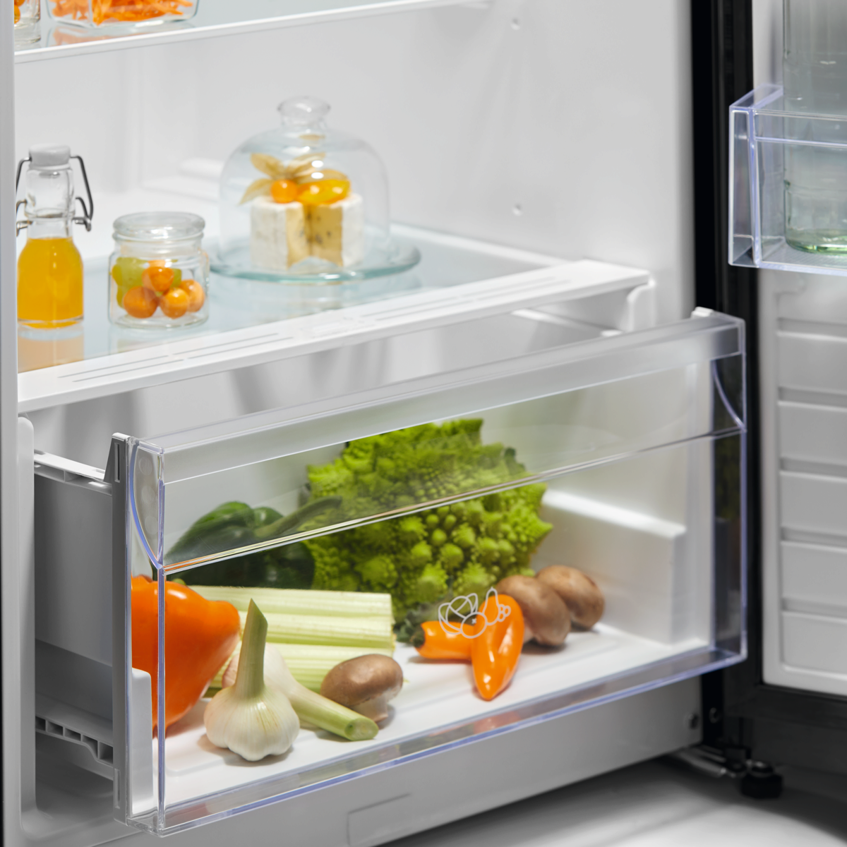 Open Electrolux refrigerator with a crisper drawer containing vegetables