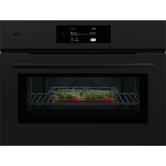Black AEG combi oven with a dish of vegetables inside on a white background