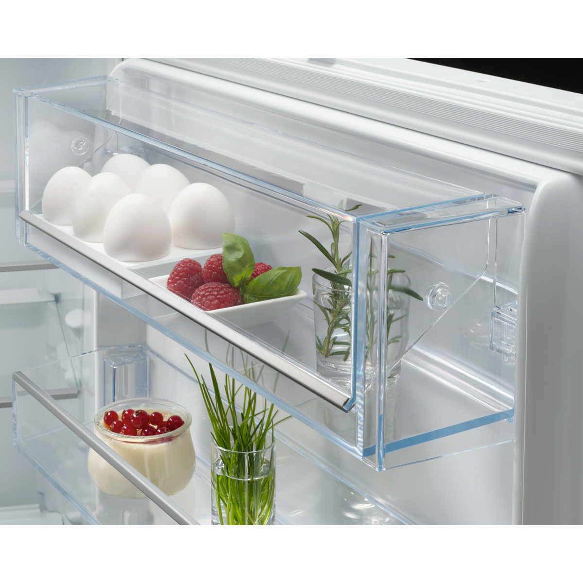 Open AEG refrigerator drawer with eggs, berries, and herbs inside