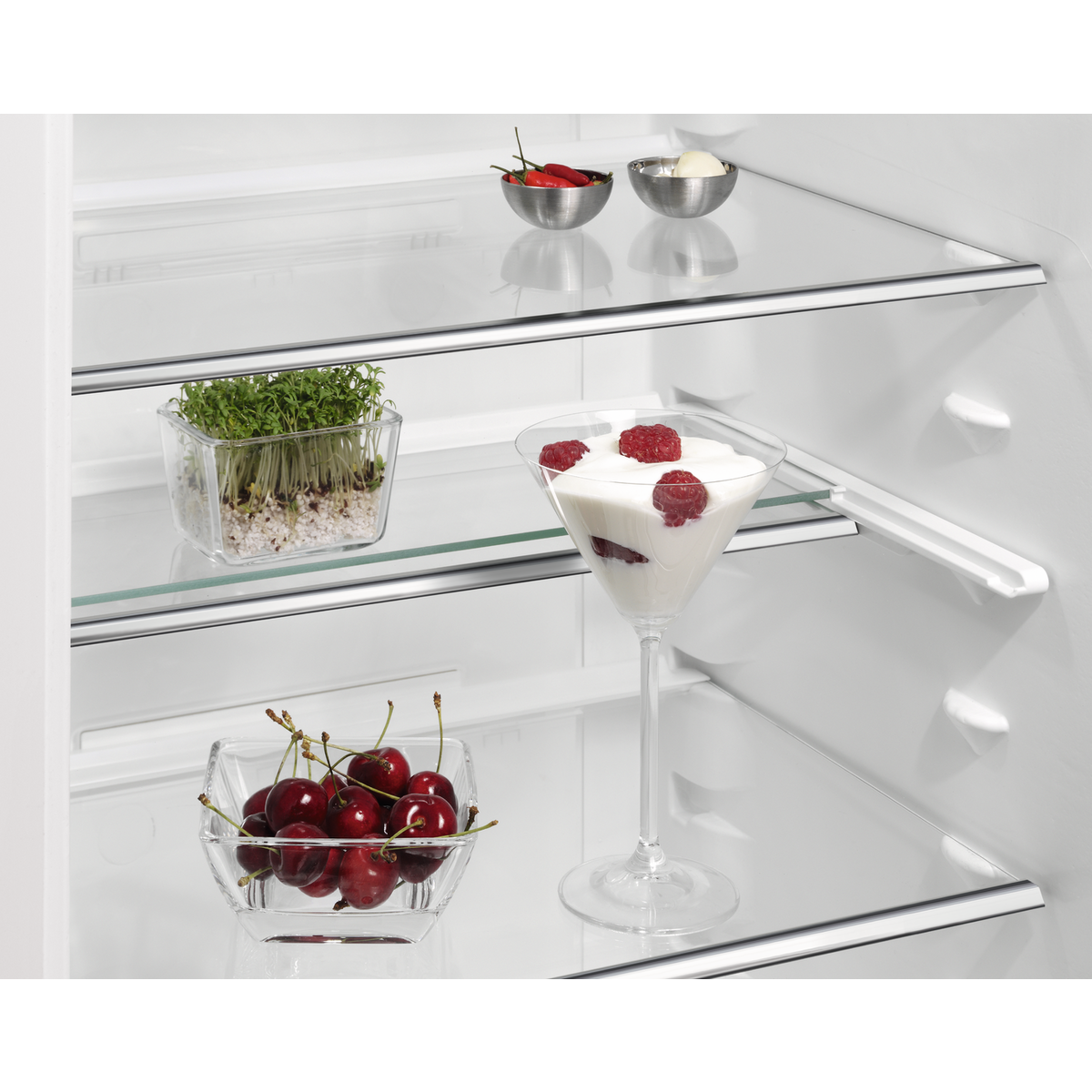 Glass shelves in an AEG refrigerator with fruits and vegetables.
