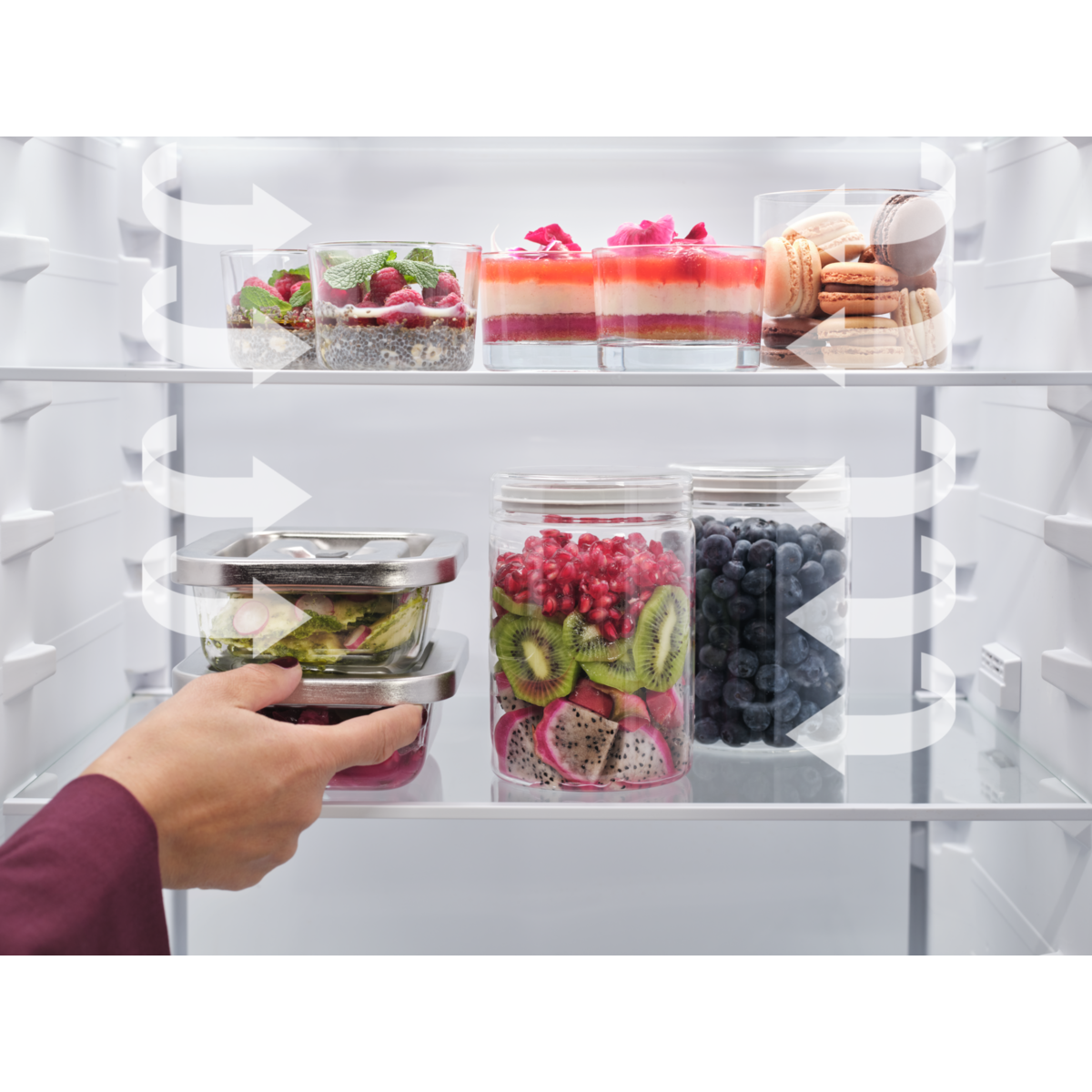 Person organizing food containers in an AEG refrigerator with various food items.
