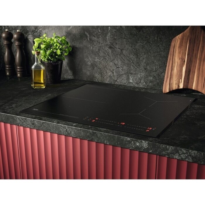 Black AEG SaphirMatt induction Hob on a kitchen counter with decorative items.